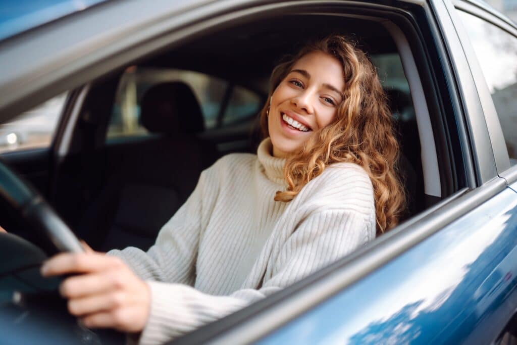 woman smiling and looking out of her car window